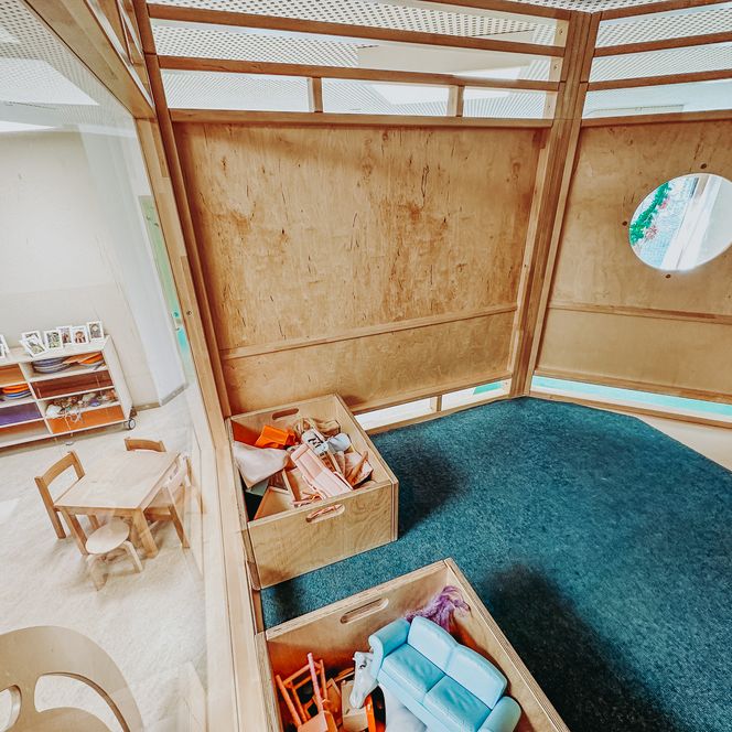 Holzspielhaus mit Teppichboden, Kisten mit Spielsachen und kleiner Sitzecke in der KiTa Soderstorf.