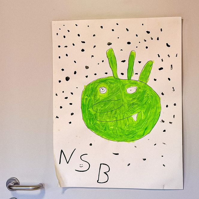 Kinderzeichnung eines grünen Monsters mit drei Fühlern und dem Schriftzug „NSB“.