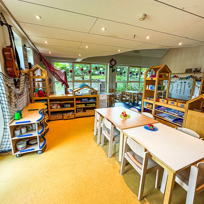 Kreativbereich im Kindergarten Oldendorf/Luhe mit Tischen, Regalen voller Materialien und Musikinstrumenten an der Wand.