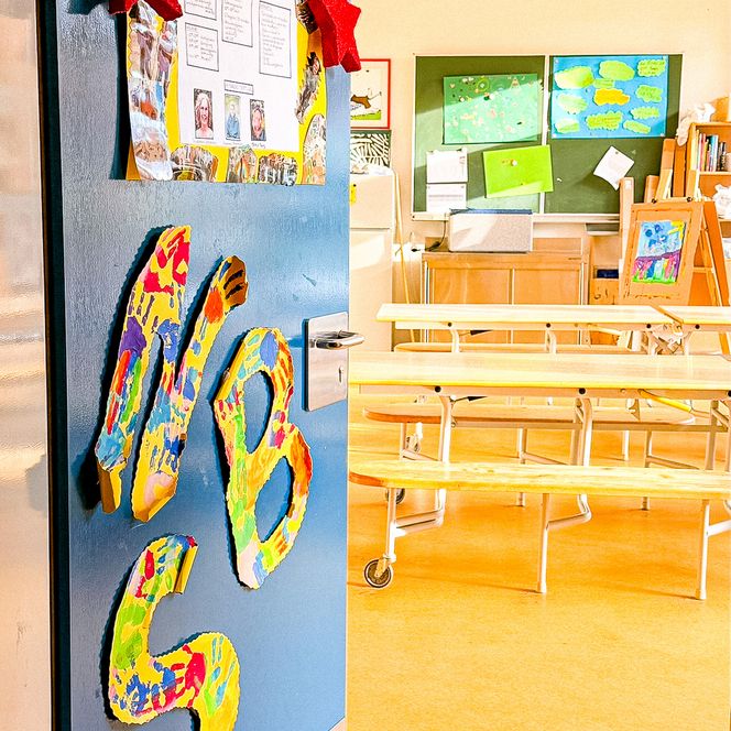 Blick durch eine offenstehende, bunt mit dem Schriftzug „NSB Soderstorf“ dekorierte Tür in den hellen Gruppenraum der nachschulischen Betreuung.