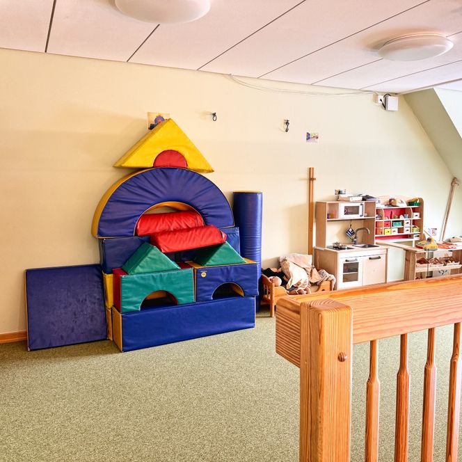 Ein Spielzimmer im Kindergarten mit großen bunten Schaumstoffbausteinen und einer Spielküche aus Holz.