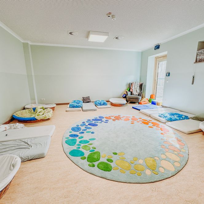 Heller Ruheraum der KiTa Soderstorf mit Matratzen, Sitzkissen, Körben und einem gemütlichen Sessel.