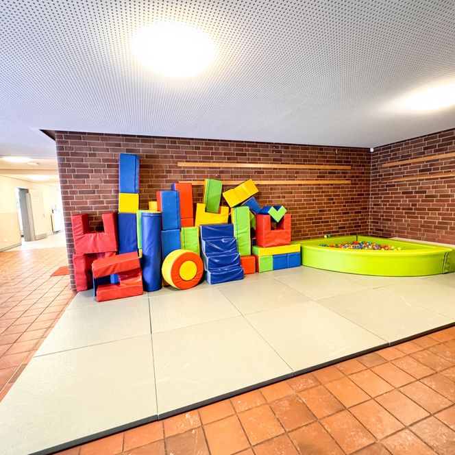 Ein Spielbereich im Kindergarten mit bunten Schaumstoffbausteinen und einem kleinen grünen Bällebad.