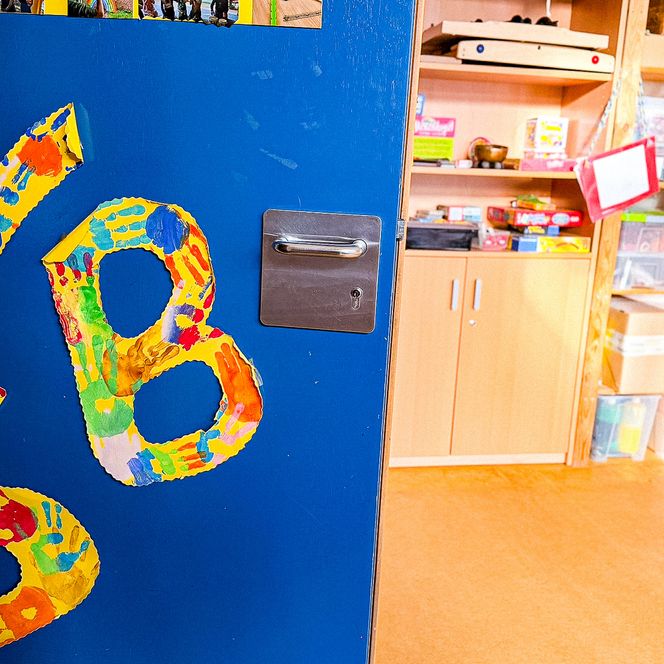 Bunte Tür mit den Buchstaben „NSB“, gestaltet aus Handabdrücken von Kindern.
