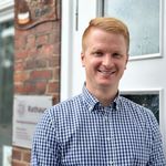 „Finn Block, Allgemeiner Vertreter des Samtgemeindebürgermeisters und Geschäftsbereichsleiter Inneres & Ordnung, steht lächelnd vor dem Eingang des Rathauses der Samtgemeinde Amelinghausen.“