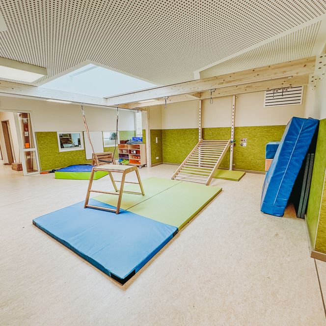 Turnraum der KiTa Soderstorf mit bunten Matten, Klettergeräten, Schaumstoffelementen und einer Hängeschaukel.