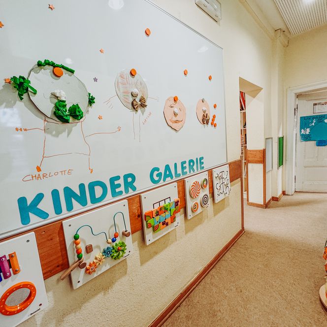 Flurbereich in der Kita Betzendorf mit einer Kinder-Galerie aus Bastelarbeiten, Spieltafeln und kreativer Wandgestaltung.
