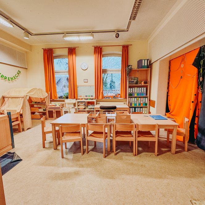 Puppenecke in der Kita Betzendorf mit Spielküche, Regalen, Verkleidungskostümen und bunter Papierketten-Dekoration.