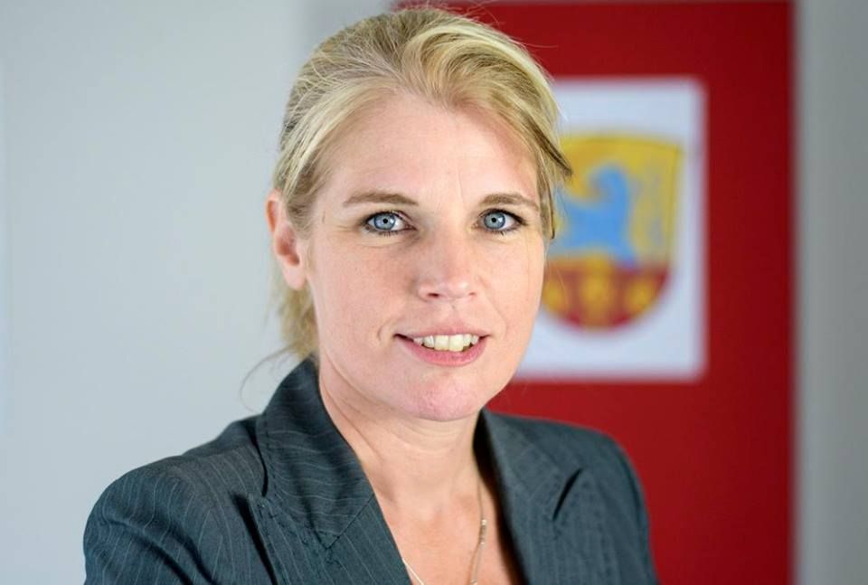 Porträt von Claudia Kalisch, ehemalige Samtgemeindebürgermeisterin von Amelinghausen, vor dem offiziellen Wappen-Hintergrund.