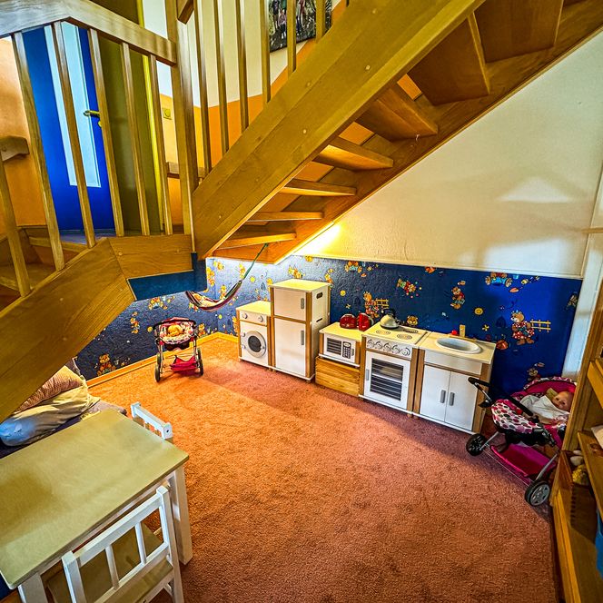 Spielbereich mit Spielküche im Kindergarten Oldendorf/Luhe mit kleinem Tisch und Stühlen, Puppenwägen, Herd, Kühlschrank und Waschbecken.
